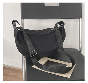 Detail view of black crescent shoulder bag featuring nylon material and adjustable strap