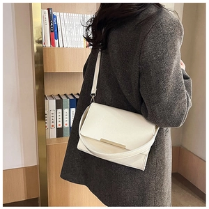 Detail view of cream white minimalist crossbody bag with gold metal trim and adjustable strap