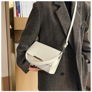 Detail of white textured shoulder bag with gold metal clasp on a grey blazer outfit