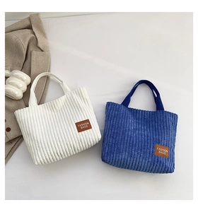 Close-up of textured corduroy tote bags in white and blue with fashion leather labels