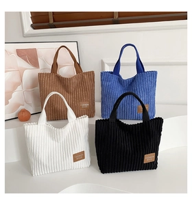 Detail view of corduroy tote bags in brown, blue, white and black colors on display