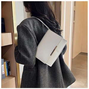 Close-up of cream white shoulder bag with gold metal trim and flap closure detail