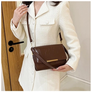 Detail of dark brown vintage faux leather crossbody bag with gold metal trim and flap cover