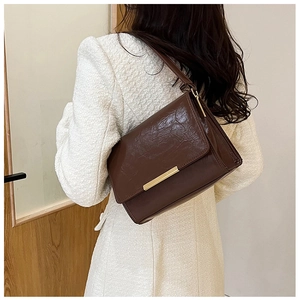 Detail of vintage brown shoulder bag showing retro waxed leather and gold metal buckle