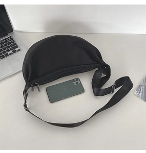 Top view of black crescent crossbody bag showing double zipper and adjustable strap