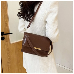 Detailed back view of a brown vintage leather shoulder bag with gold metal trim bar