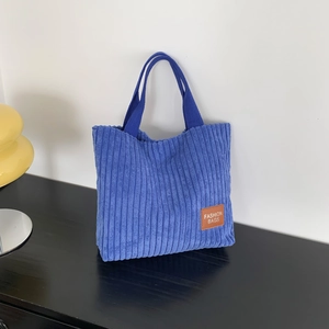 Minimalist navy blue corduroy tote bag with dual handles and leather logo patch