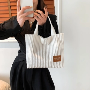 Minimalist white corduroy tote bag with fashion leather patch held by a model