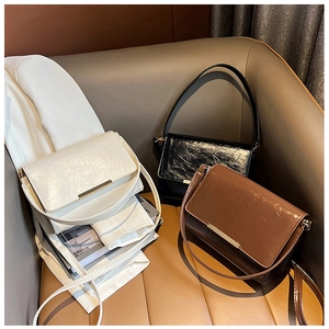 Three minimalist flap shoulder bags in cream, black, and tan with gold buckles