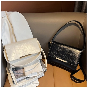 Detail of minimalist rectangular shoulder bags in cream white and glossy black textures