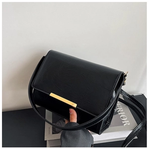 Detail of black pleated faux leather bag featuring a gold buckle and textured surface