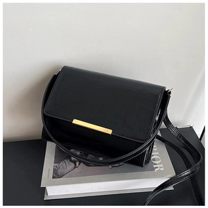 Close-up of black textured faux leather handbag featuring a minimalist gold buckle detail