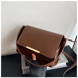 Detail shot of vintage brown square bag with wrinkled texture and gold metal bar