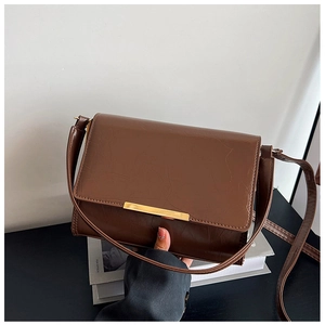 Detail shot of a coffee brown crossbody bag featuring textured leather and a golden metal clasp