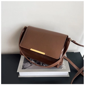 Detail shot of a retro brown crossbody bag with gold buckle on a magazine background