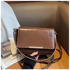 Close-up of brown vintage leather crossbody bag with oily texture and gold metal detail