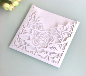 Macro detail of laser-cut white wedding invitation with elegant rose pattern