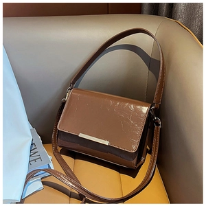 Detailed shot of dark brown retro shoulder bag with glossy oil finish and metal buckle
