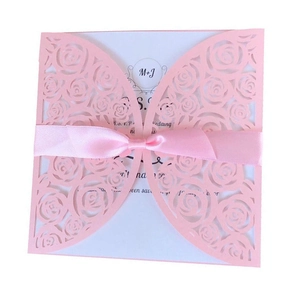 Detail of pink laser-cut wedding invitation with rose pattern and satin ribbon bow