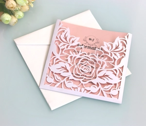 Detail of laser-cut rose hollow wedding invitation with pink inner card and envelope