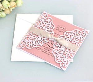 Elegant laser cut white floral wedding invitation set with pink card and champagne ribbon