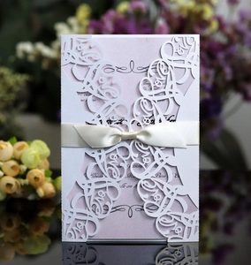 Detailed laser-cut white LOVE invitation with pearl paper insert and satin bow ribbon