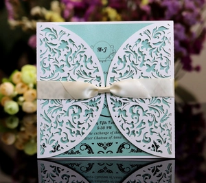 Détail de l'invitation de mariage découpée au laser avec dentelle et ruban vert menthe