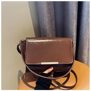 Close-up of dark coffee vintage textured shoulder bag with silver metallic bar accent