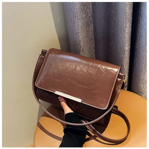 Detail of vintage dark brown crossbody bag featuring glossy crinkled leather and silver hardware