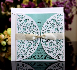 Détail macro d'une invitation de mariage découpée au laser avec motifs floraux et ruban