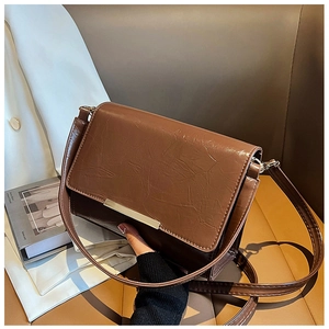 Detail of vintage brown textured leather shoulder bag with elegant gold metal trim