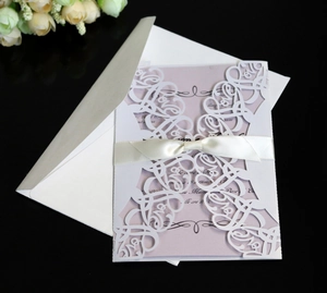 Close-up of white laser-cut LOVE invitation with purple card and satin bow detail