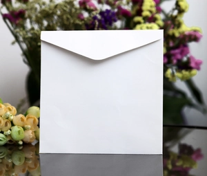 Detailed view of a white square wedding envelope with a triangular flap on a floral background
