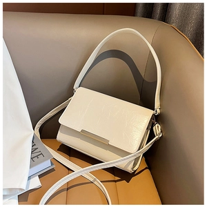 Detail of minimalist beige textured leather shoulder bag with sleek gold metal accent on cover
