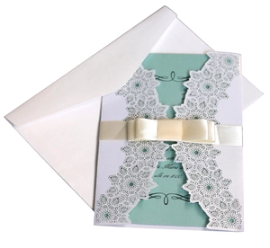 Detail of laser-cut wedding invitation with white lace pattern and mint blue card
