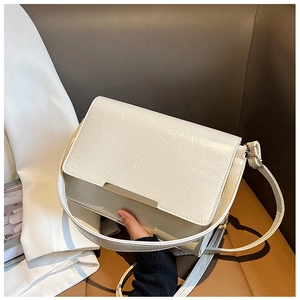 Detail of cream glossy shoulder bag with crinkled texture and gold metal trim