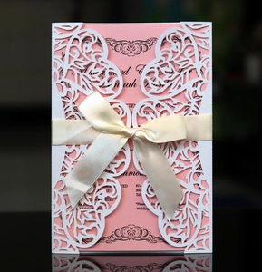 Detaillierte lasergeschnittene weiße Blumenmuster auf Hochzeitseinladung mit rosa Karte