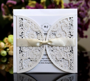 Detail of laser-cut butterfly wedding invitation with elegant champagne ribbon bow