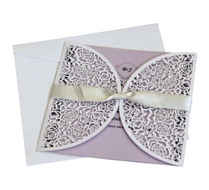 Detail of laser-cut rose hollow invitation with light purple card and ivory satin ribbon