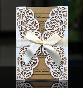 Nahaufnahme der lasergeschnittenen weißen Hochzeitseinladung mit beige Schleife