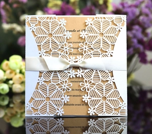 Detail showing white laser-cut snowflake invitation sleeve with brown kraft paper and ribbon