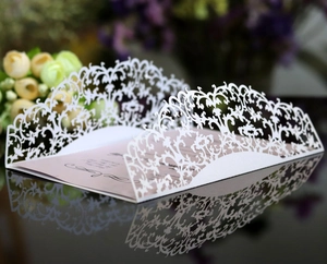 Elegant laser-cut lace wedding invitation card with floral patterns and pink insert
