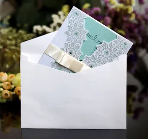 Detailed laser-cut floral wedding invitation with mint green insert and satin ribbon bow