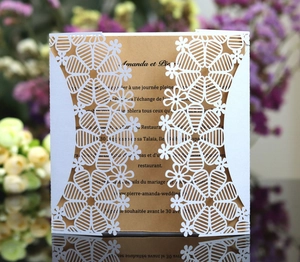Close-up of laser-cut white snowflake invitation with elegant floral lace and gold insert