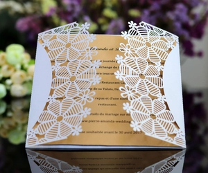 Macro detail of laser-cut white snowflake invitation with elegant gold insert card