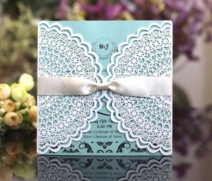 Elegant white laser-cut lace wedding invitation with light blue card and satin ribbon bow