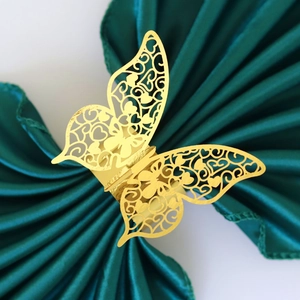 Elegant gold laser-cut butterfly napkin ring on dark green satin for wedding table decor