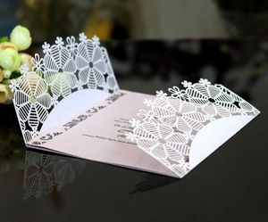 Elegant white laser-cut snowflake invitation with pink inner card and floral details