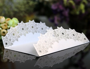 Close-up of white laser-cut wedding invitation with intricate lace hollow patterns