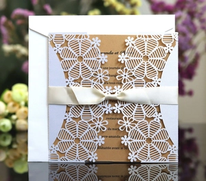 Elegant laser-cut white snowflake invitation set with kraft insert and white satin ribbon